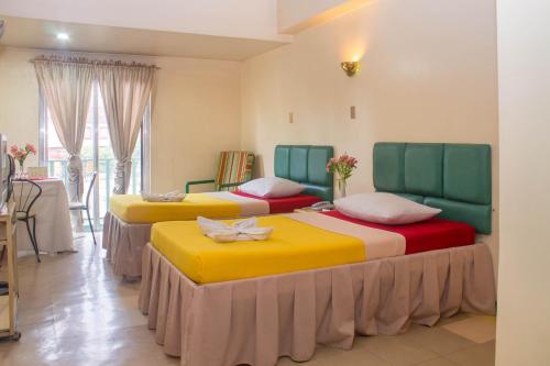 碧瑶Benguet Prime Hotel的黄色和红色的房间里设有三张床