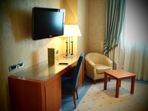 佩鲁贾普鲁萨酒店的酒店客房设有一张桌子,墙上配有电视