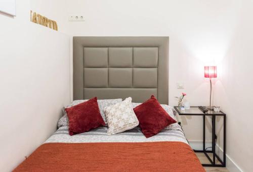 马德里瑞拉托雷斯街公寓的一间卧室配有一张带红色枕头的床和一张桌子