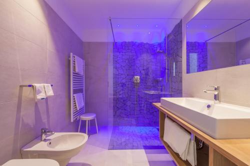 圣坎迪朵思科芬霍夫酒店的浴室配有水槽和带紫色照明的淋浴