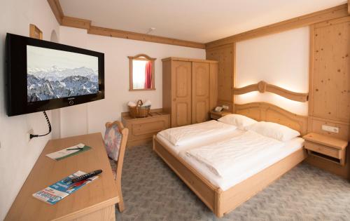 图克斯绿色之门酒店的一间卧室配有一张床、一张书桌和一台电视