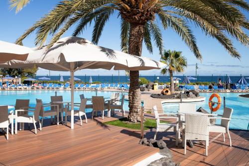 科斯塔特吉塞特贵司普拉亚大酒店的一个带游泳池的度假村和一个带椅子和遮阳伞的甲板