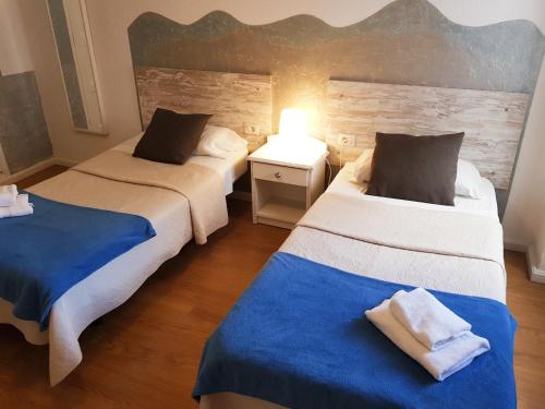 圣克鲁斯-德特内里费地平线酒店的一间卧室配有两张带蓝白色床单的床