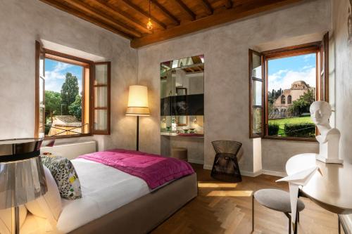 罗马Palm Suites - Small Luxury Hotels of the World的一间卧室配有一张床、一张书桌和两个窗户。