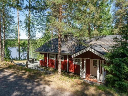HirsjärviHoliday Home Satakieli by Interhome的一座红色的小房子,树林里设有一个车库