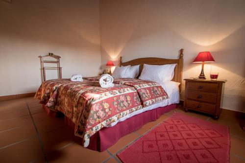 AzinhagaCasas da Piedade的一间卧室配有一张带红色毯子和床头柜的床
