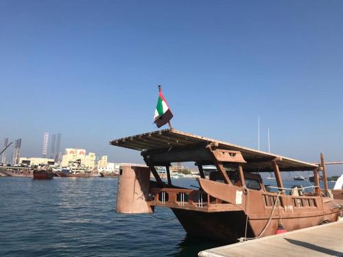 沙迦Al Majarah Residence的船,船上悬挂着旗帜,坐在水里