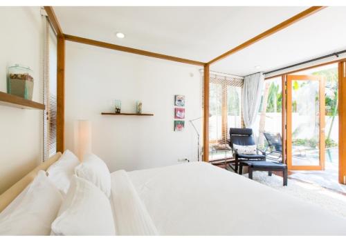 盼武里普拉纳鲁克斯泳池度假屋旅馆的卧室配有白色的床和椅子