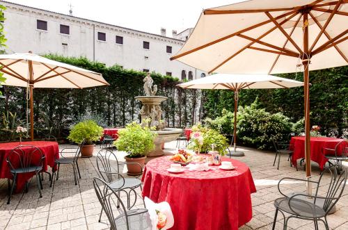 威尼斯贝里亚缇酒店的一个带桌椅和遮阳伞的庭院