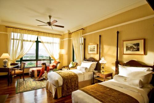 马六甲The Majestic Malacca Hotel - Small Luxury Hotels of the World的坐在旅馆房间,带两张床的女人