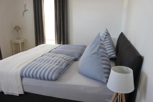 阿尔特费尔rosmarin-am-sund的一张带蓝色和白色枕头的床和一盏灯