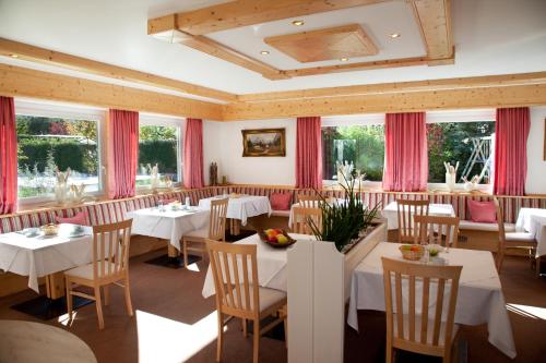 纳图尔诺拉尔臣霍夫酒店的餐厅设有白色的桌椅和窗户。