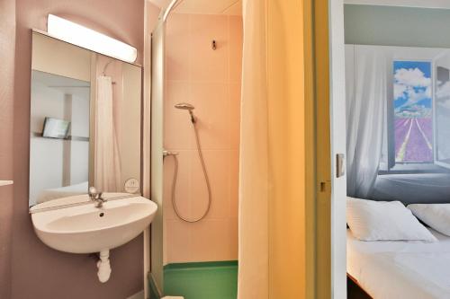 莱斯托雷特斯B&B HOTEL Montélimar Nord的浴室设有水槽和床边的镜子