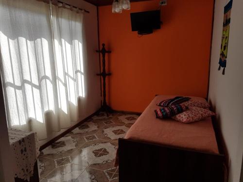 拉马约Las Casitas de Emilia的一间卧室设有橙色墙壁、一张床和一个窗户
