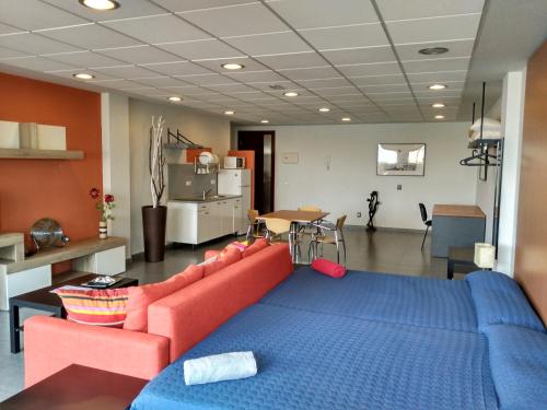 罗萨里奥港Studio Loft Fuerteventura的客厅配有红色沙发和蓝色的床