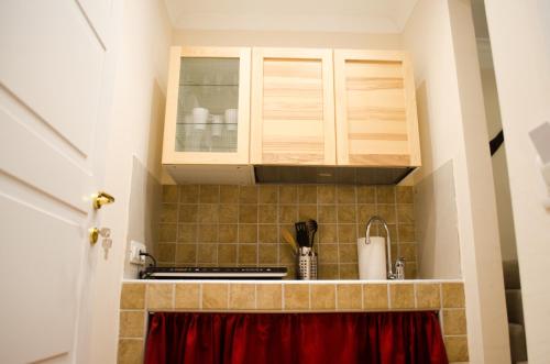 那不勒斯B&B Sosta Flegrea的厨房配有木制橱柜和红色窗帘