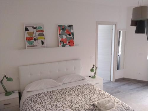 坎波巴索Novantatrè的白色卧室配有一张床,墙上挂有绘画作品