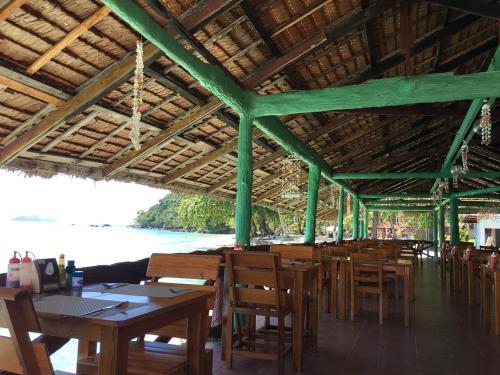 奈岛乃岛度假酒店的餐厅设有木桌和椅子,并有水体