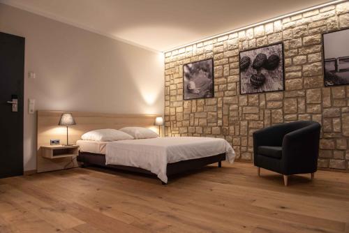 佩尔Wein Erlebnis Hotel Maimühle的一间卧室设有一张床和石墙