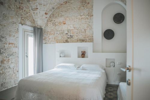洛科罗通多Pietra Pesara的卧室配有白色的床和砖墙