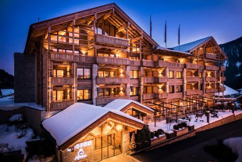 毛拉赫Cocoon - Alpine Boutique Lodge的一座大木结构建筑,在晚上下雪