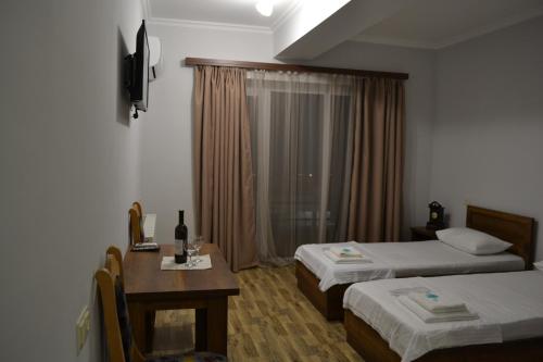 泰拉维The Wine Hotel Telavi的酒店客房设有两张床、一张桌子和一个窗户。