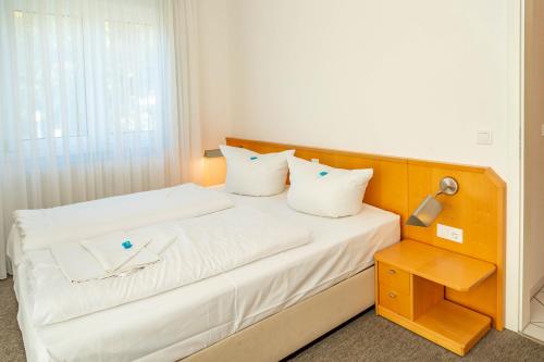 岑平Apartment Astra的一张带白色床单和枕头的床