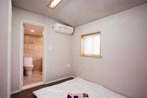 西归浦市书签旅馆的浴室设有床、卫生间和窗户。