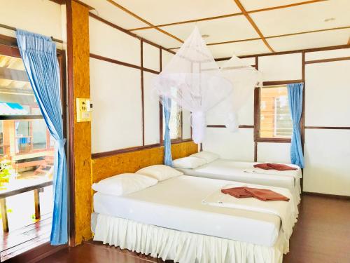 利邦岛利邦海滩度假酒店的配有蓝色窗帘的客房内的两张床