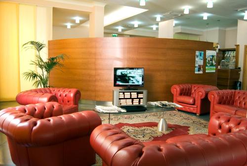 拉奎拉圣米歇尔酒店的一间设有红色皮椅和平面电视的等候室