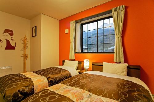 由布市汤布院旅舍的橙色墙壁和窗户的客房内的两张床