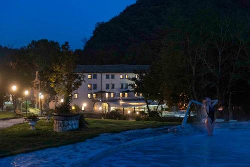 卡纳莱蒙特拉诺Hotel Terme di Stigliano的一个人在晚上在游泳池玩耍