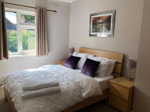 沃里克Comfortable House in Warwick的一间卧室配有一张带紫色枕头的床和窗户。