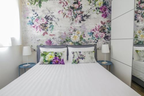 博洛尼亚Charming and cosy apartment的一张带两个枕头的白色床和花卉墙