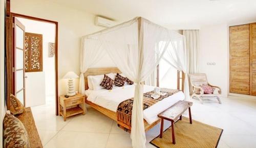 坎古别墅霎哈嘉酒店的一间卧室配有一张天蓬床和一把椅子
