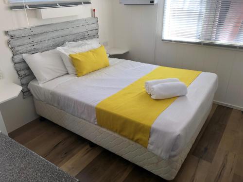 圣殿海岬棕榈滩大篷车公园酒店的一间卧室配有一张带黄色和白色枕头的大床