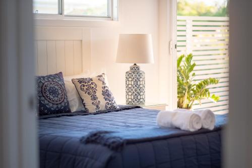 木麻黄Serenity Beach Retreat的一间卧室配有蓝色的床、枕头和窗户