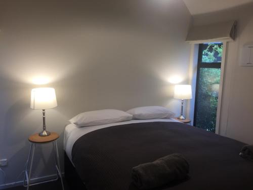 特卡波湖Black Beech House with Stunning Outdoor Bath的一间卧室配有一张带两盏灯的床和一扇窗户。