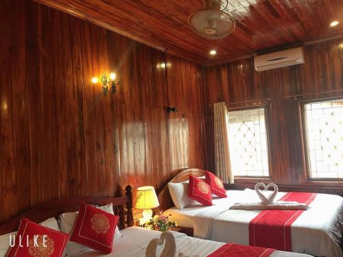 琅勃拉邦苏提考恩1号酒店的一间卧室设有两张床和木镶板墙