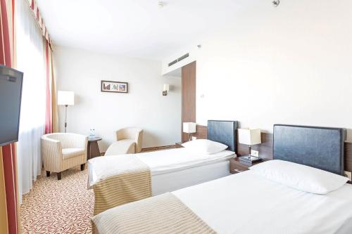 罗兹罗兹Qubus酒店的酒店客房设有两张床和电视。