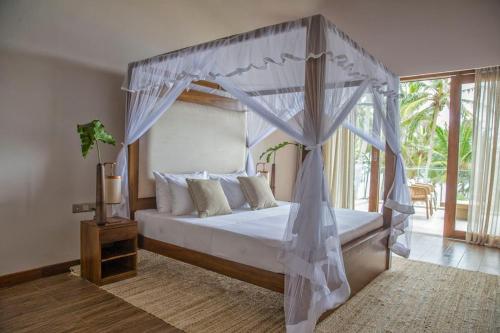 坦加拉Villa Blu的一间卧室配有一张带天蓬的床