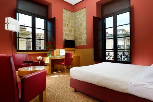 那不勒斯UNAHOTELS Napoli的酒店客房带一张床、一张桌子和椅子