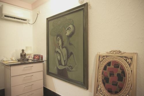 加尔各答Reena's Lodge的梳妆台旁边的墙上画着两幅女人的画
