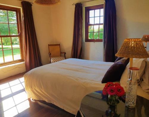 安德伯格Pear Tree Cottage-Underberg的一间卧室配有一张床和一张鲜花桌子