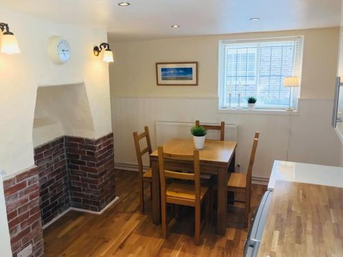 格雷夫森德Wisteria Cottage的一间带桌子和砖砌壁炉的用餐室