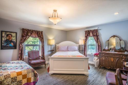 德兰赫勒Heartwood Inn的一间卧室配有一张床、一个梳妆台和两个窗户。