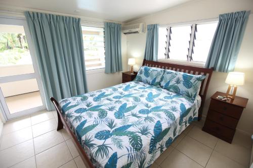 拉罗汤加珊瑚金沙公寓酒店的一间卧室配有一张带蓝色和白色床单的床。