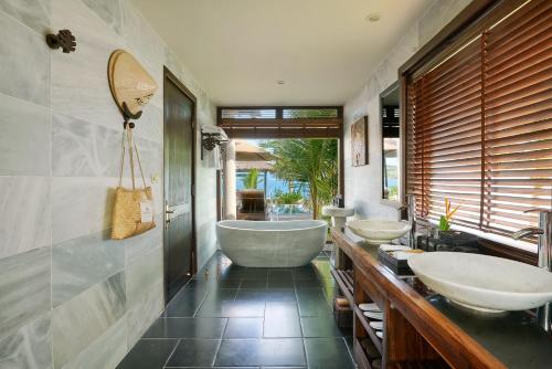 芽庄Amiana Resort Nha Trang的浴室配有3个盥洗盆和浴缸。