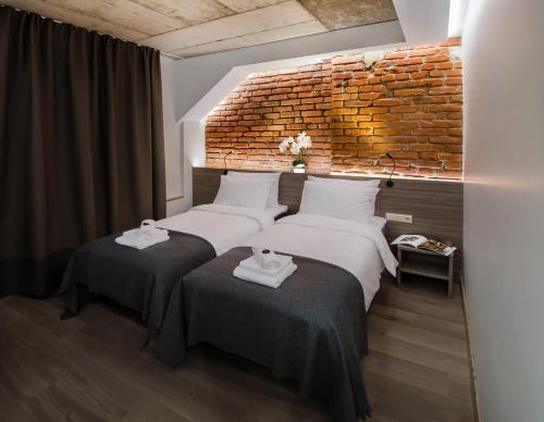 克莱佩达Dangė Hotel的砖墙客房的两张床