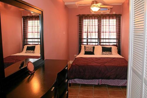 巴斯特尔CosyNest的一间卧室配有两张床、一张桌子和两个窗户。